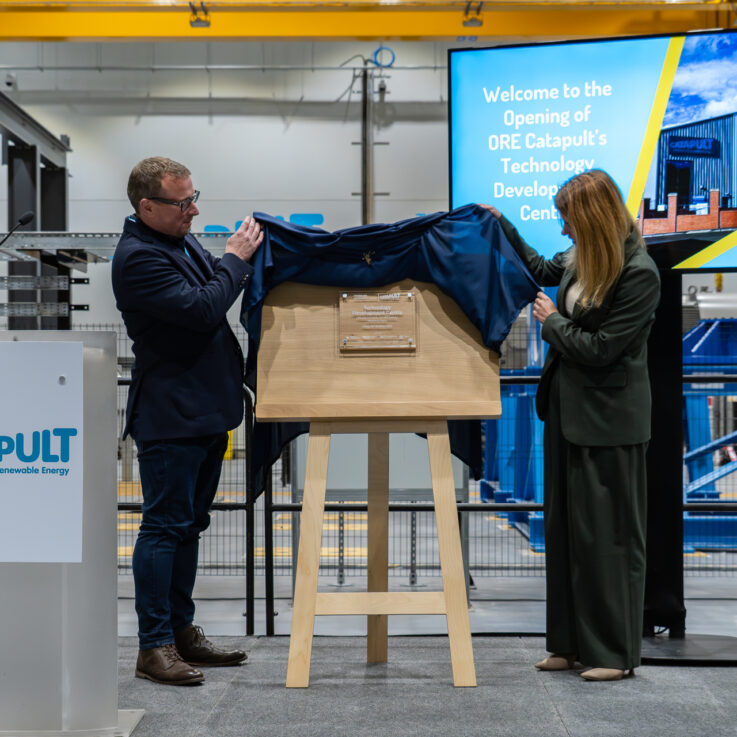 Two people unveiling a plaque